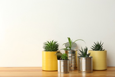 Beautiful houseplants in tin cans on wooden table. Space for text