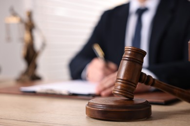 Notary writing notes at wooden table in office, focus on gavel