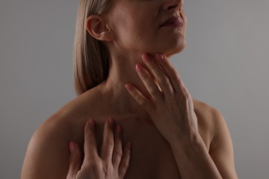 Photo of Woman touching her neck on grey background, closeup