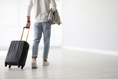 Man with black travel suitcase in airport. Space for text