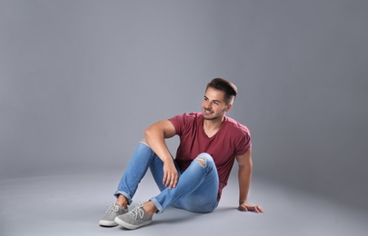 Young man in stylish jeans on grey background