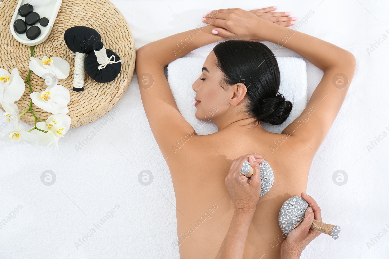 Photo of Young woman receiving herbal bag massage in spa salon, top view