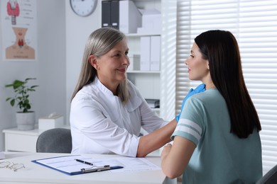 Endocrinologist examining thyroid gland of patient at table in hospital