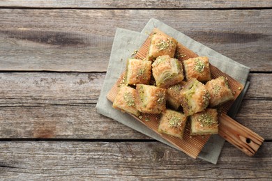 Photo of Delicious fresh baklava with chopped nuts on wooden table, top view and space for text. Eastern sweets