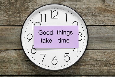 Photo of Phrase Good Things Take Time and clock on wooden table, top view. Motivational quote