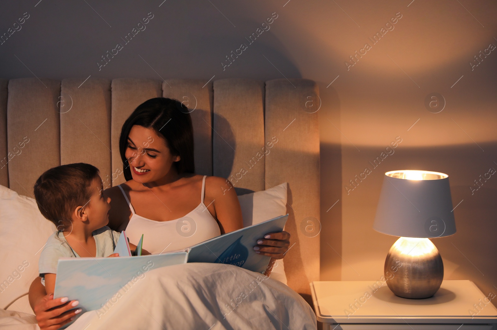 Photo of Mother reading bedtime story to her son at home