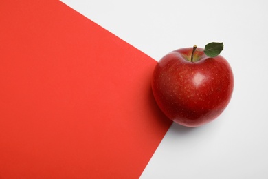 Photo of Ripe juicy red apple with leaf on color background, top view. Space for text