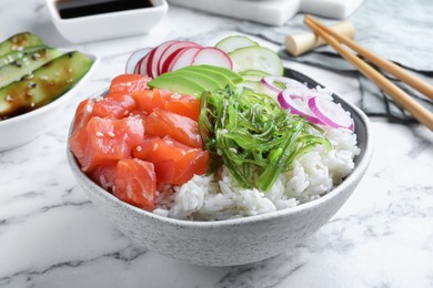 Photo of Delicious poke bowl with salmon and vegetables served on white marble table, closeup