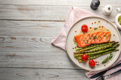 Photo of Tasty grilled salmon with tomatoes, asparagus and spices served on wooden table, flat lay. Space for text