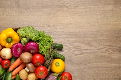 Photo of Different fresh vegetables on wooden table, flat lay. Space for text