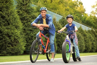 Photo of Dad and son riding modern bicycles outdoors