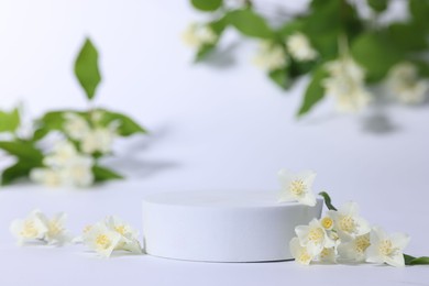 Presentation of product. Podium and beautiful jasmine flowers on white background