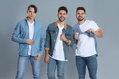 Group of young men in stylish jeans on grey background
