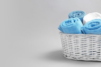 Photo of Basket with soft bath towels on grey background