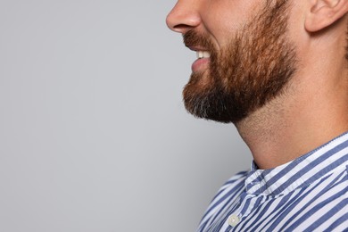 Photo of Profile portrait of smiling bearded man on grey background, closeup. Space for text