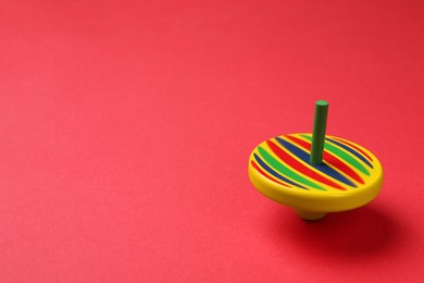 One colorful spinning top on red background, space for text