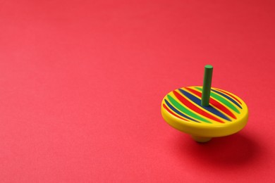 Photo of One colorful spinning top on red background, space for text