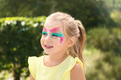 Photo of Cute little girl with face painting outdoors