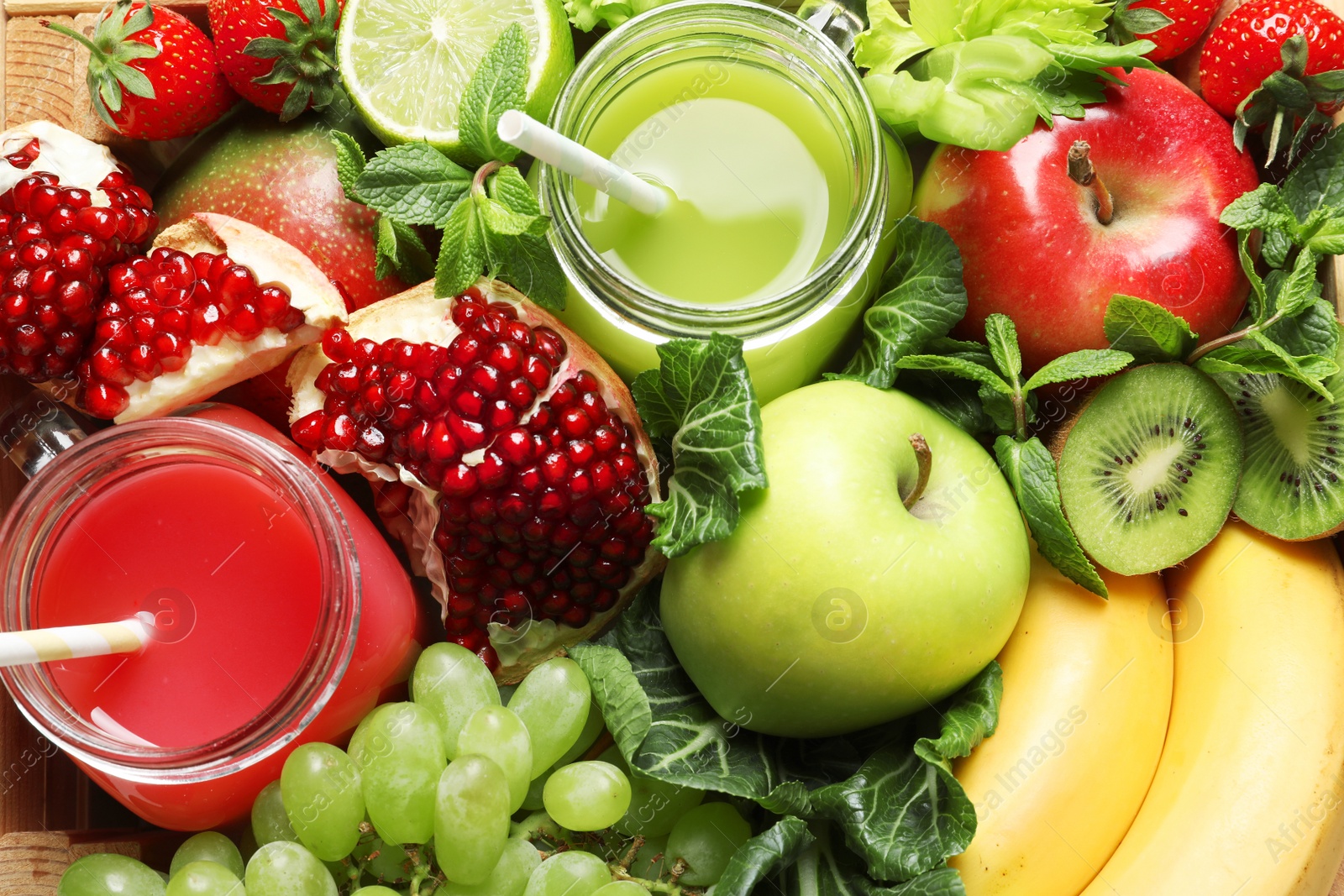 Photo of Juices in mason jars with fresh fruits in wooden crate