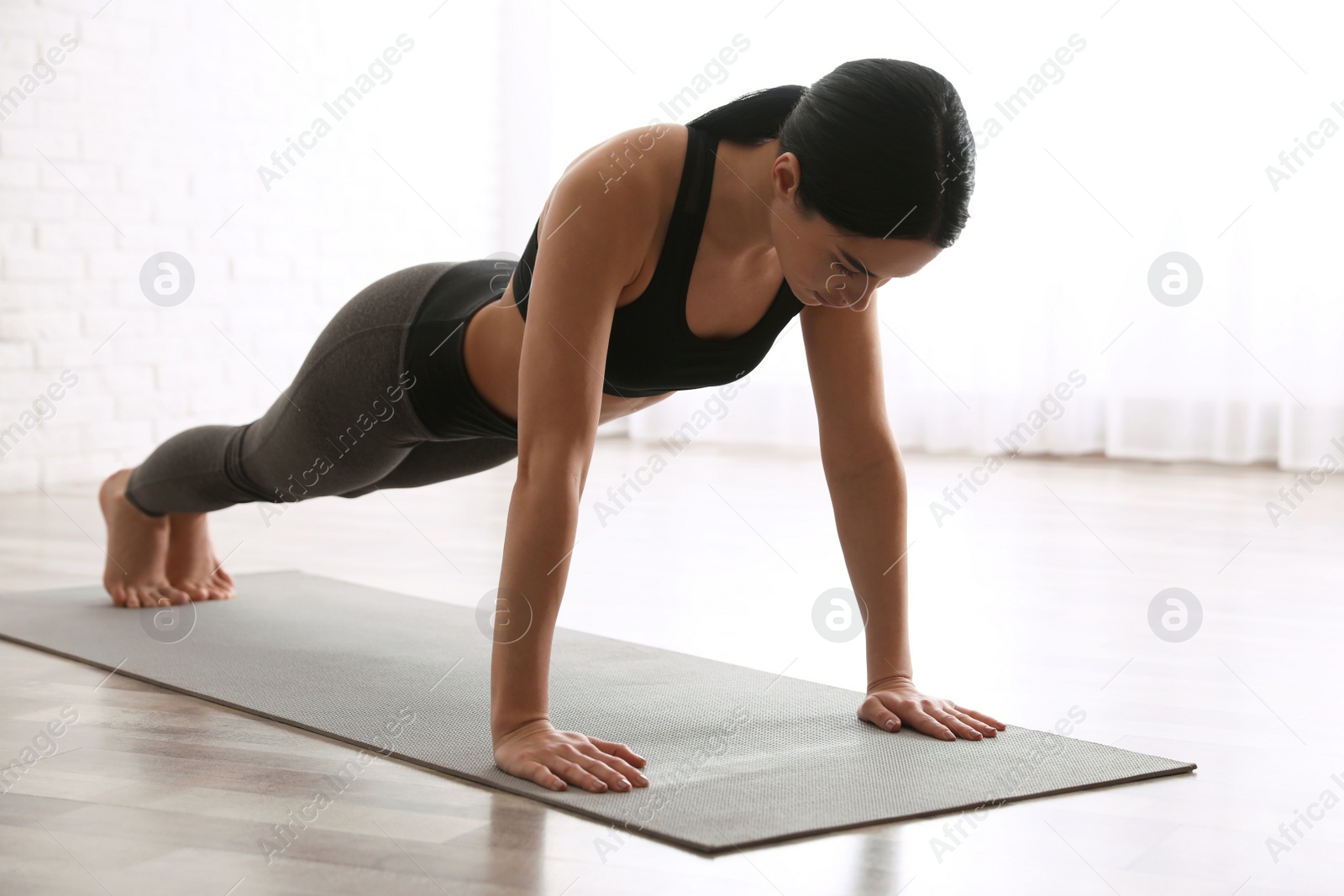 Photo of Young woman practicing plank asana in yoga studio. Phalankasana pose