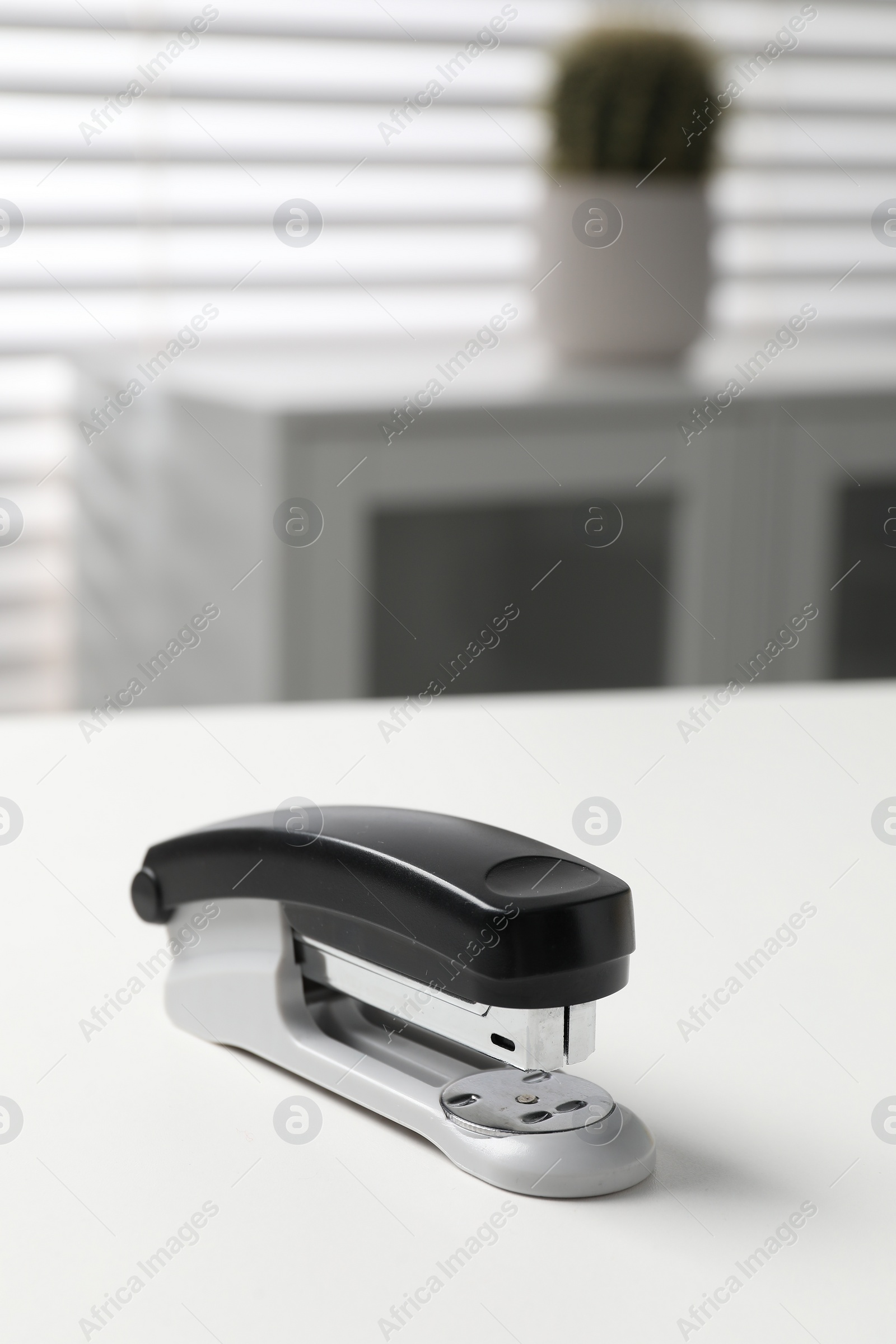 Photo of One stapler on white table indoors, closeup