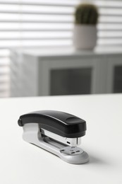 Photo of One stapler on white table indoors, closeup