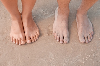 Happy young couple at beach on sunny day, closeup of feet