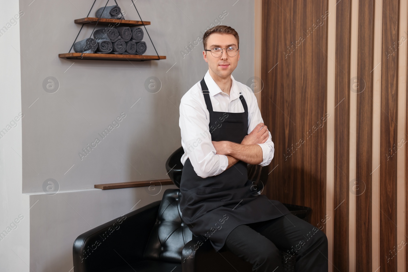 Photo of Portrait of professional hairdresser wearing apron in beauty salon