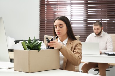 Dismissed woman packing personal stuff into box in office