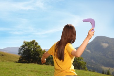 Photo of Woman throwing boomerang in mountains, back view. Space for text