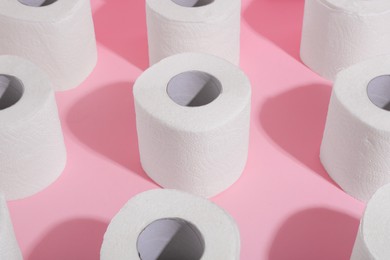 Photo of Many soft toilet paper rolls on pink background, closeup