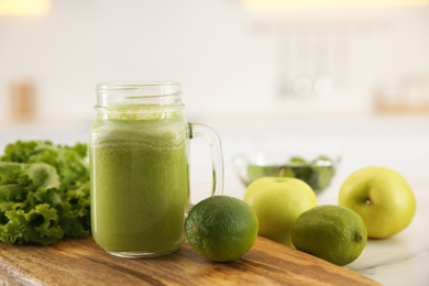 Photo of Tasty fresh juice in mason jar on board indoors, closeup. Space for text