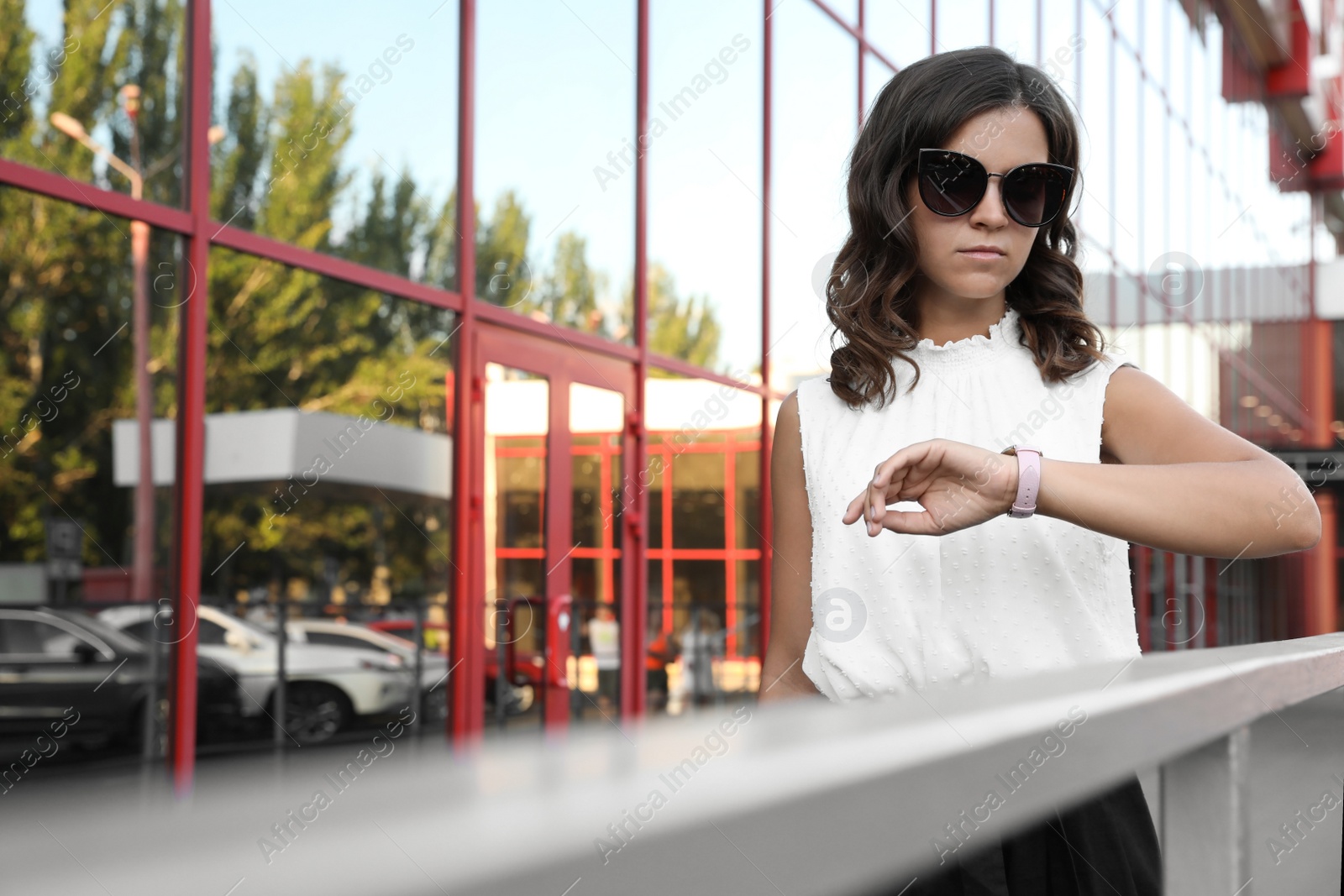 Photo of Young woman checking time on city street