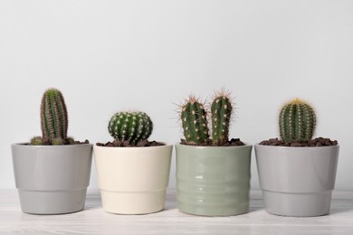 Different cacti in pots on white wooden table