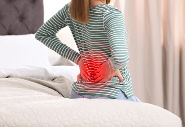 Image of Woman suffering from back pain after sleeping on uncomfortable mattress at home, closeup