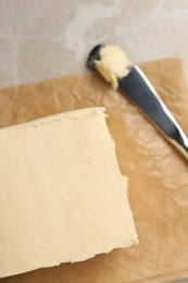 Block of tasty butter and knife on light table, top view