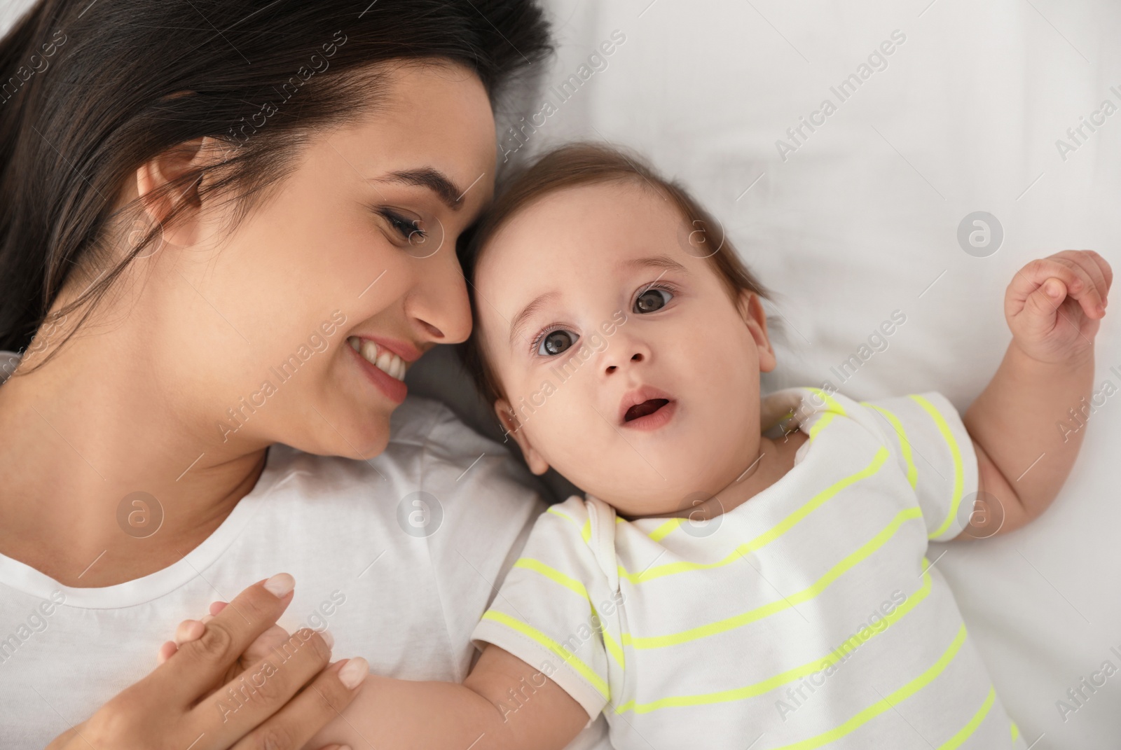 Photo of Portrait of mother with her cute baby lying on bed, top view