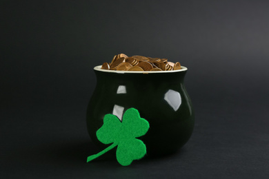 Photo of Pot of gold coins and clover on black background. St. Patrick's Day celebration