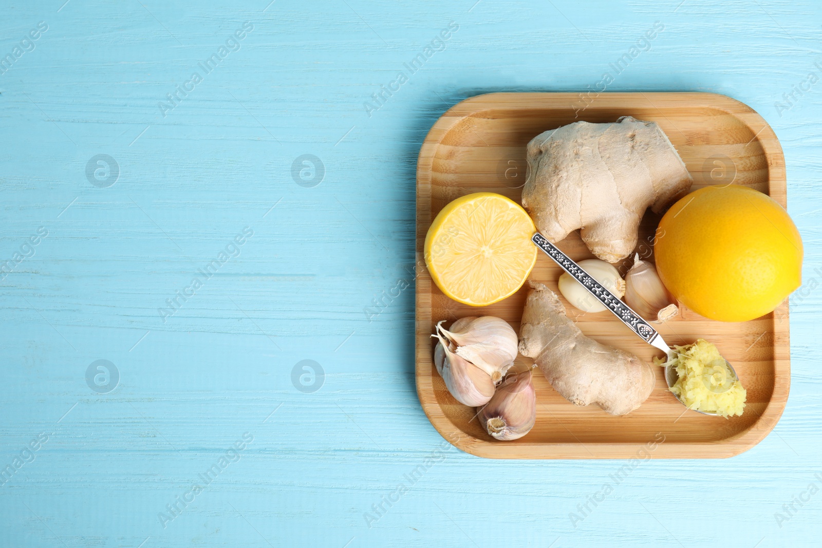 Photo of Fresh garlic and other natural cold remedies on light blue wooden table, top view. Space for text