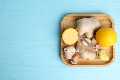 Photo of Fresh garlic and other natural cold remedies on light blue wooden table, top view. Space for text