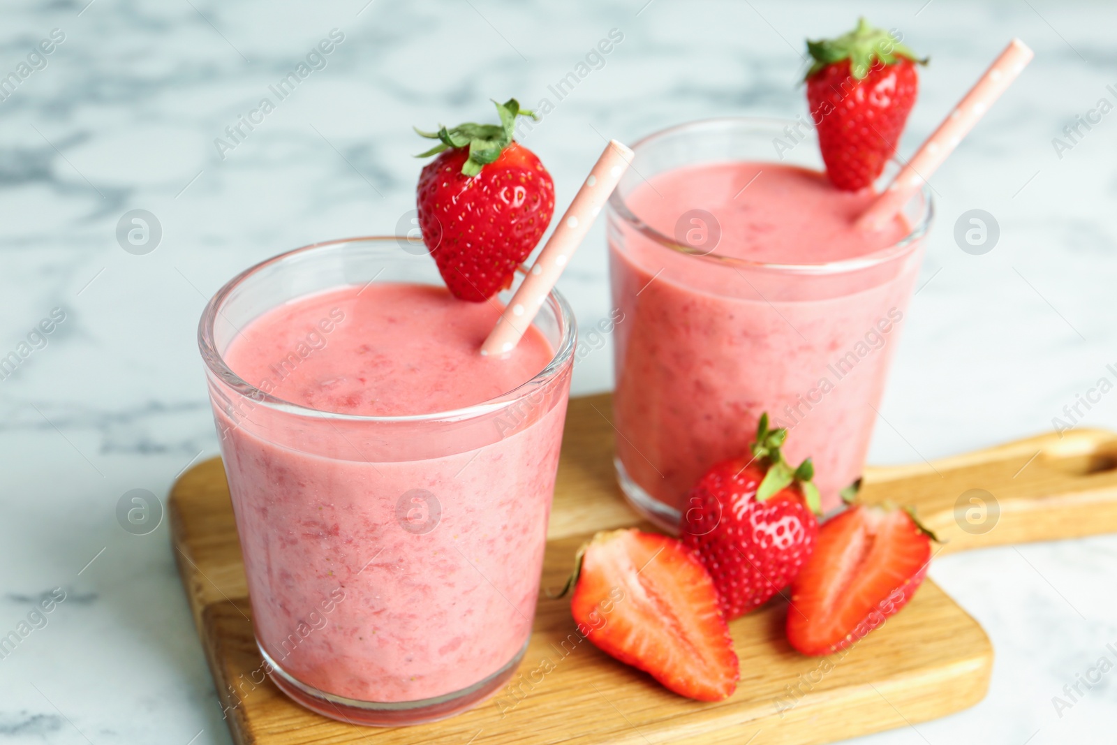 Photo of Tasty strawberry smoothies in glasses on wooden board