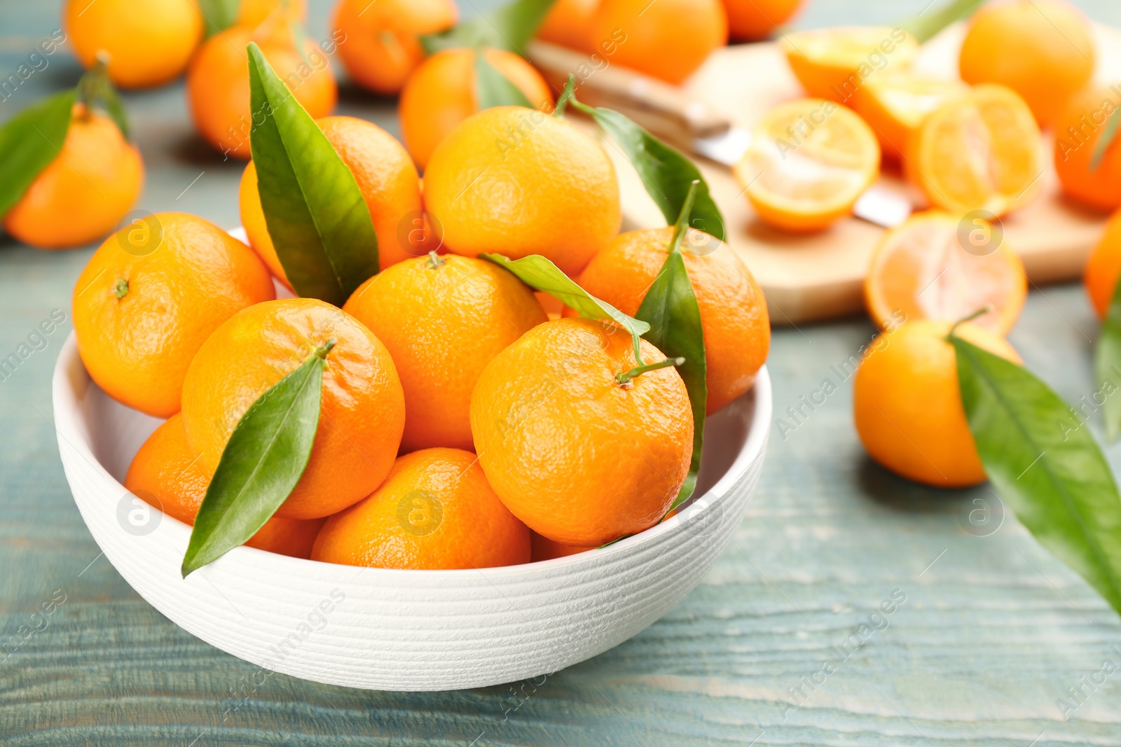 Photo of Fresh tangerines with green leaves on blue wooden table, closeup. Space for text