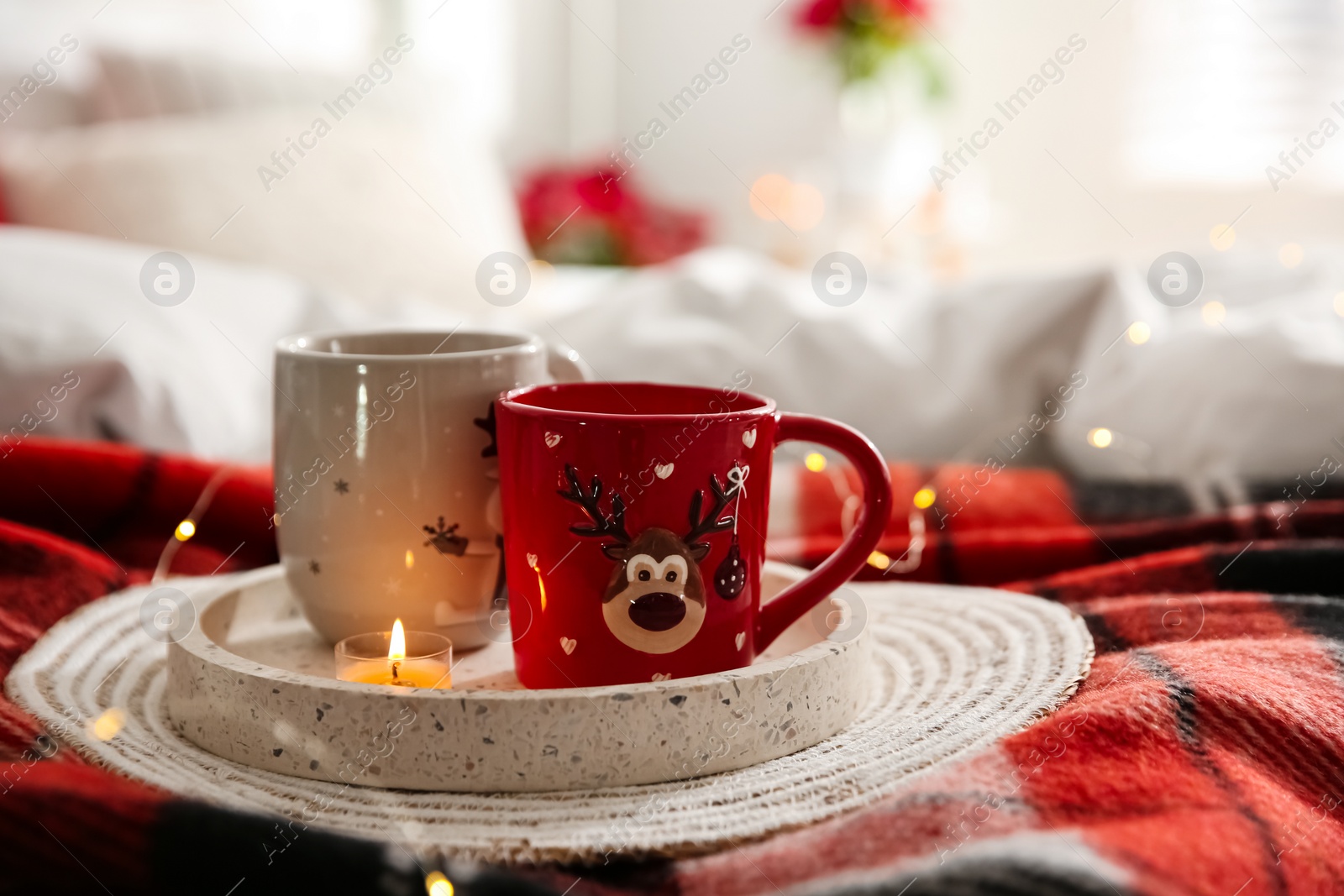 Photo of Christmas cups in tray on red woolen blanket. Interior decor