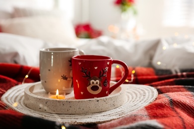 Photo of Christmas cups in tray on red woolen blanket. Interior decor