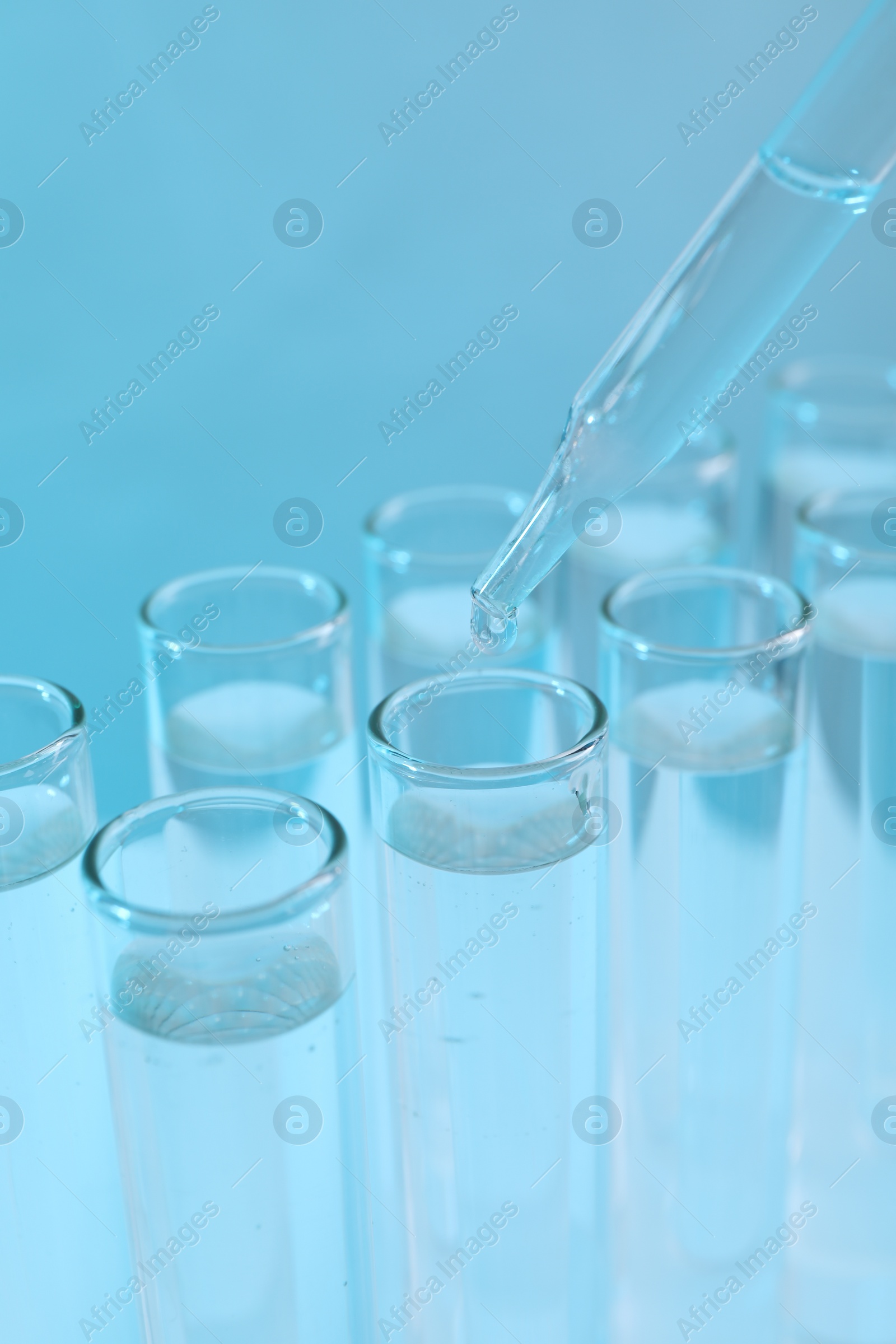 Photo of Laboratory analysis. Dripping reagent into test tube on light blue background, closeup