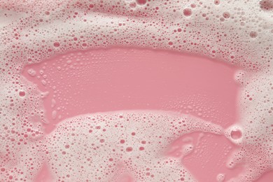 Photo of White washing foam on pale pink background, top view