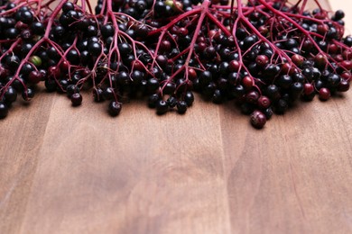 Photo of Tasty elderberries (Sambucus) on wooden table, space for text
