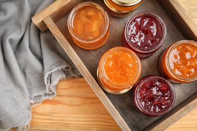 Photo of Jars with different sweet jam in wooden crate