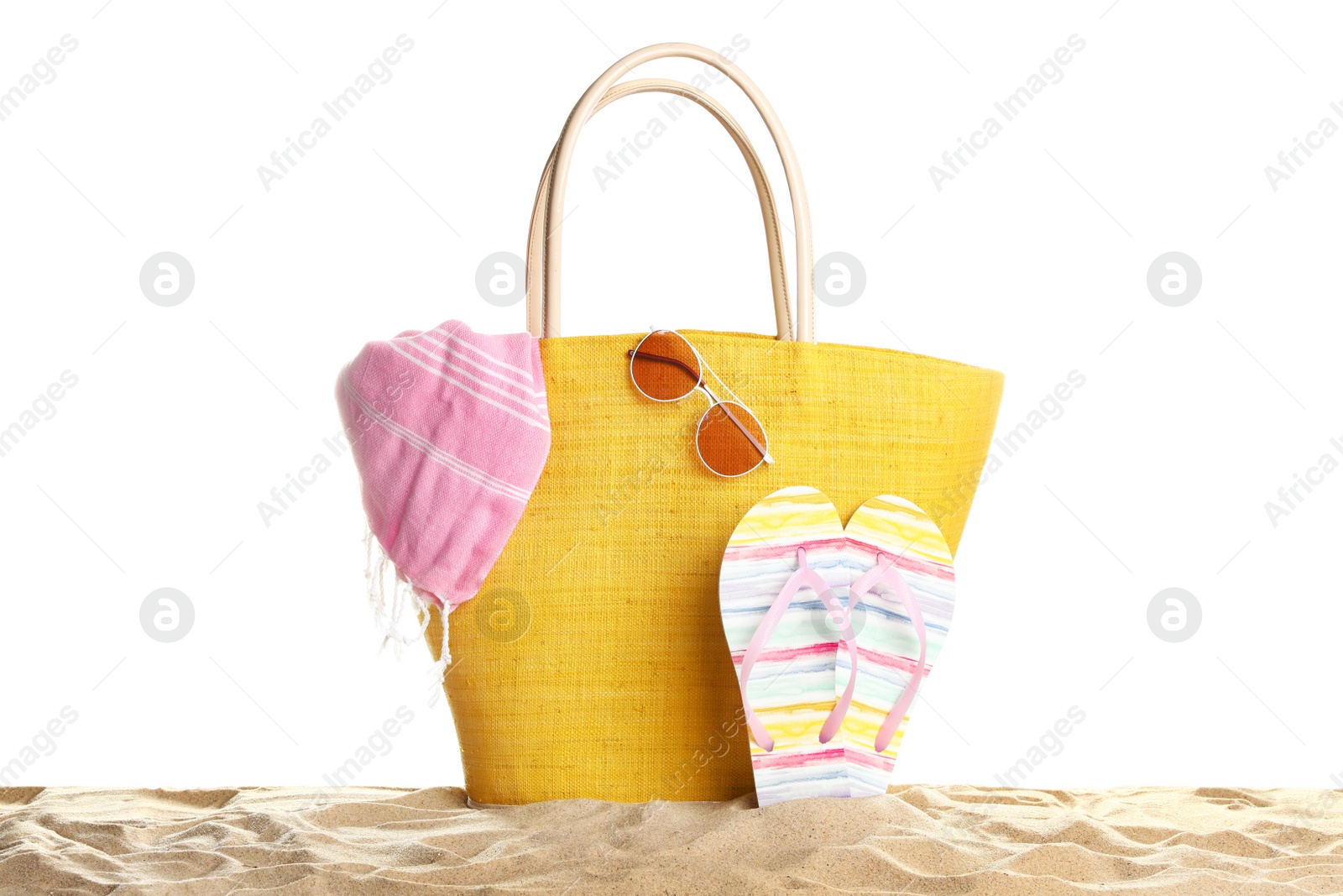 Photo of Stylish yellow bag and beach accessories on sand against white background