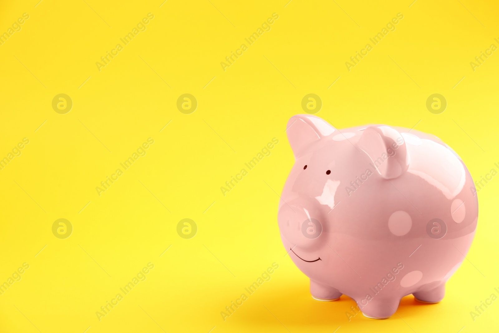 Photo of Pink piggy bank on yellow background. Space for text